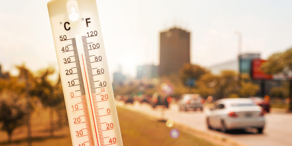 Thermometer vor Autos und Verkehr während einer Hitzewelle