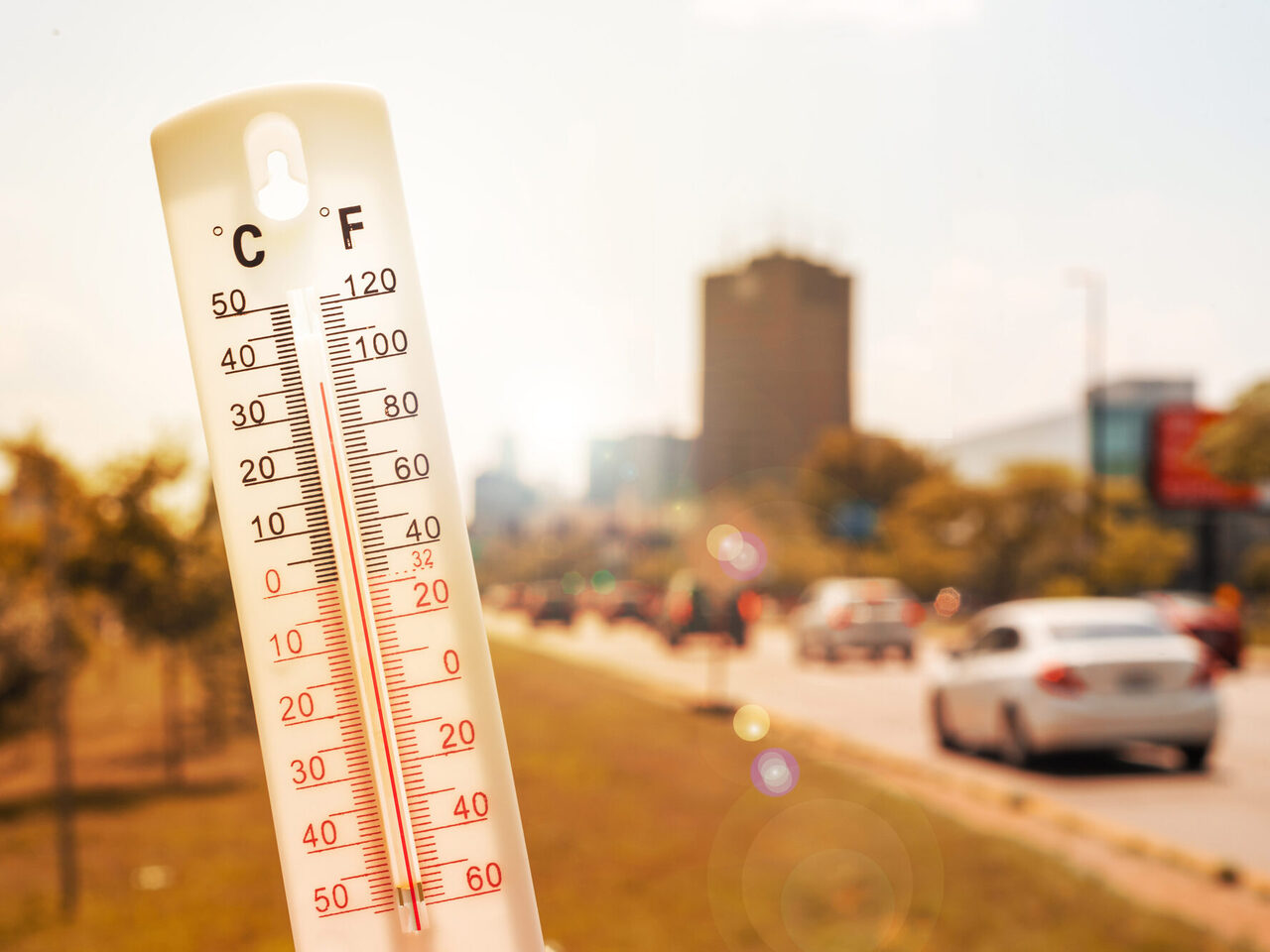 Thermometer vor Autos und Verkehr während einer Hitzewelle