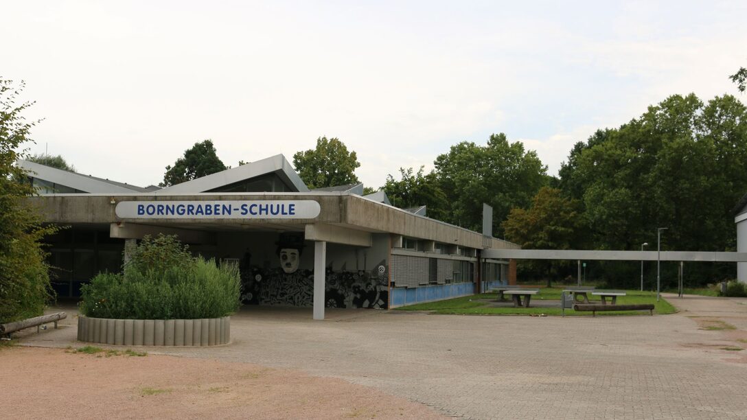 Frontalansicht der Borngraben-Schule mit Blick auf das Schulgebäude und den Schulhof nebenan.