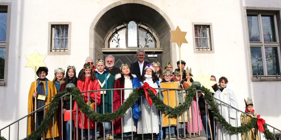 14 Sternsinger stehen mit dem Oberbürgermeister auf der Rathaustreppe