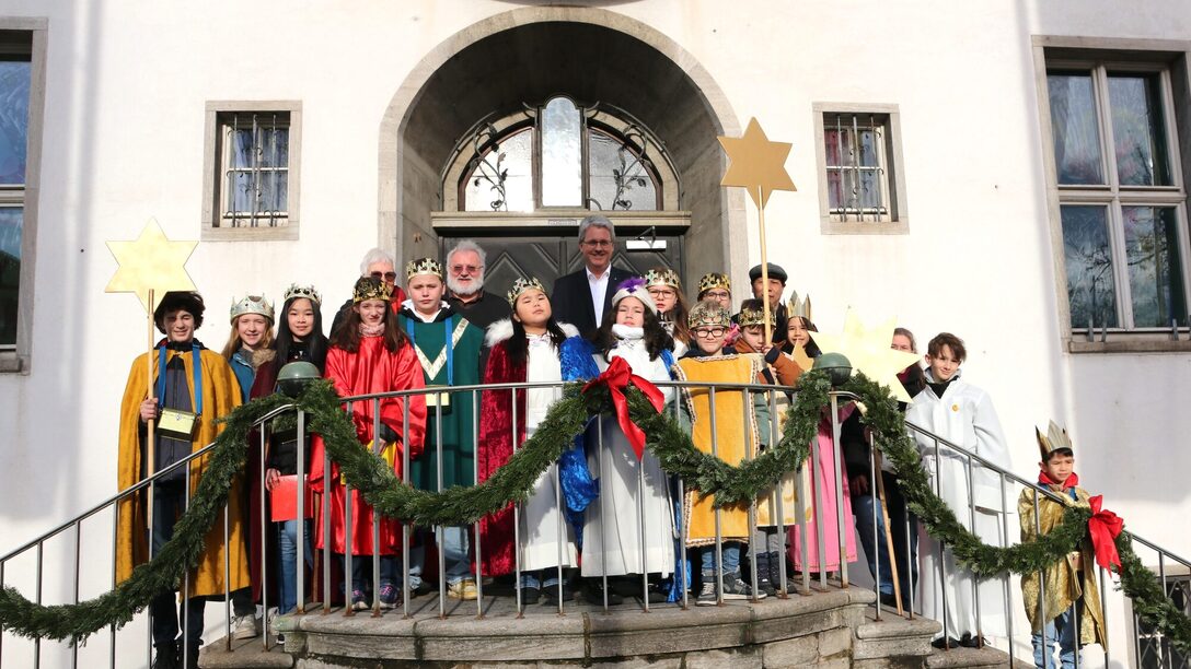 14 Sternsinger stehen mit dem Oberbürgermeister auf der Rathaustreppe