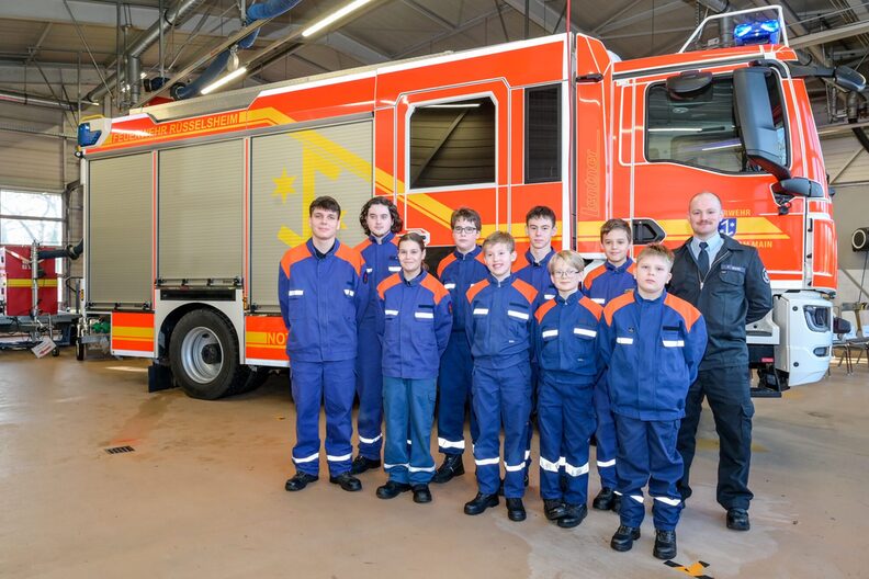 Jungen und Mädchen stehen vor dem neuen Feuerwehrfahrzeug