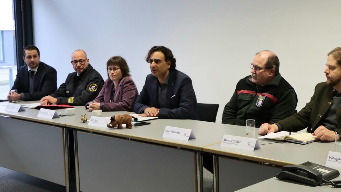 Vertreter des Kreises sitzen zur Pressekonferenz an einem langen Tisch