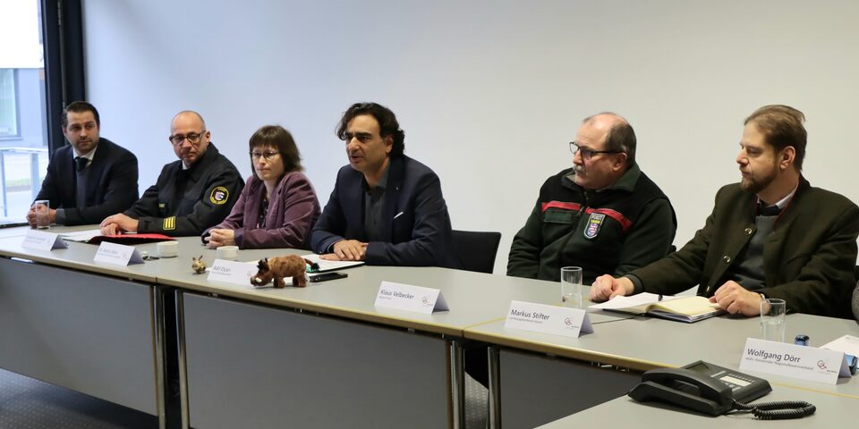 Vertreter des Kreises sitzen zur Pressekonferenz an einem langen Tisch