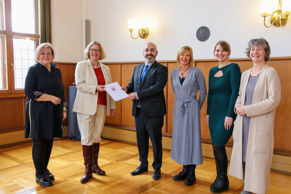 Mehrere Personenstehen im alten Ratssaal des Rathaus Rüsselsheim. v.l.n.r.: Sabine Bächle-Scholz (MdL), Staatssekretärin Katrin Hechler, Bürgermeister Murat Karakaya, Sabine Günther-Paluchowski (Sozialplanung), Anastasija Neiß (Stadtteilkoordination) und Elisabeth Israel (SPV e.V.)