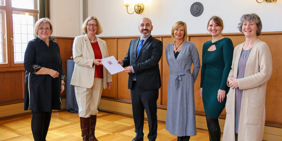 Mehrere Personenstehen im alten Ratssaal des Rathaus Rüsselsheim. v.l.n.r.: Sabine Bächle-Scholz (MdL), Staatssekretärin Katrin Hechler, Bürgermeister Murat Karakaya, Sabine Günther-Paluchowski (Sozialplanung), Anastasija Neiß (Stadtteilkoordination) und Elisabeth Israel (SPV e.V.)