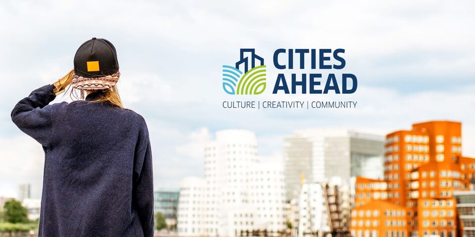 Junge Frau mit Cap von hinten, die auf eine Ansammlung von mehrstöckigen Häusern blickt. Darüber das "Cities Ahrad"-Logo