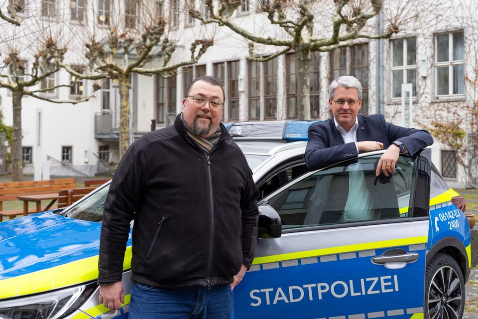 Oliver Hiß, Fachbereichsleiter Sicherheit und Ordnung, und Oberbürgermeister Patrick Burghardt stehen an Stadtpolizei-Auto im Rathaus-Innenhof.