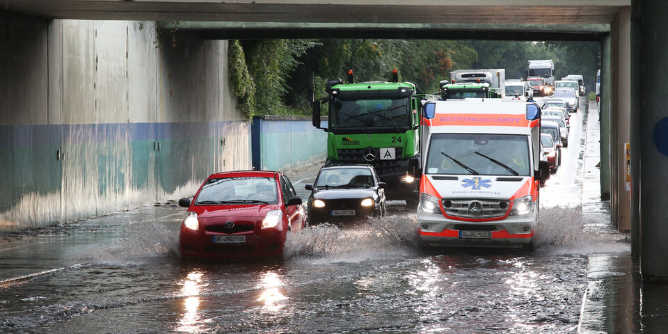 Autos fahren durch tiefes Wasser in der Unterführung Rugbyring.