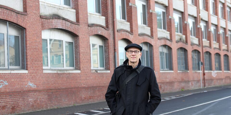 Jens Weisener steht vor der Fassade des Opel-Altwerks an der Weisenauer Straße.