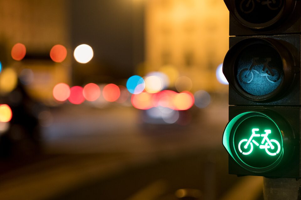 Grüne Ampel mit Fahrrad-Symbol. Lichter im Hintergrund.