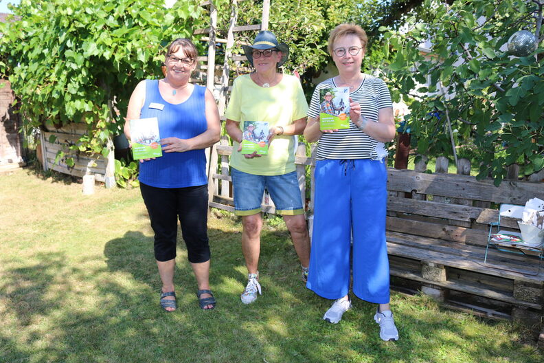 Bärbel Becker, Wilma Held und Regina Weidmann halten jeweils einen Wanderführer "Wandern mit Wilma" in den Händen