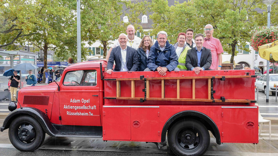 Projektgruppe um Oberbürgermeister Patrick Burghardt und Bürgermeister Dennis Grieser auf einem Fahrzeug der Opel Blitz-Feuerwehr.