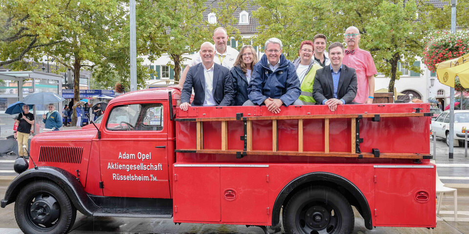 Projektgruppe um Oberbürgermeister Patrick Burghardt und Bürgermeister Dennis Grieser auf einem Fahrzeug der Opel Blitz-Feuerwehr.