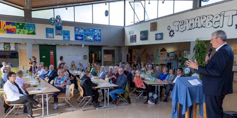 Oberbürgermeister Patrick Burghardt spricht vor einer Gruppe Menschen zum 50-jährigen Jubiläum der Borngrabenschule