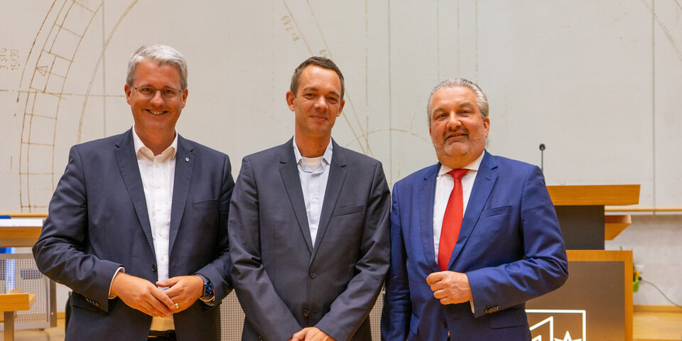 Drei Personen stehen vor einem Rednerpult. Zu sehen sind v.l.n.r. Oberbürgermeister Patrick Burghardt, Simon Valerius und Stadtverordnetenvorsteher Jens Grode.