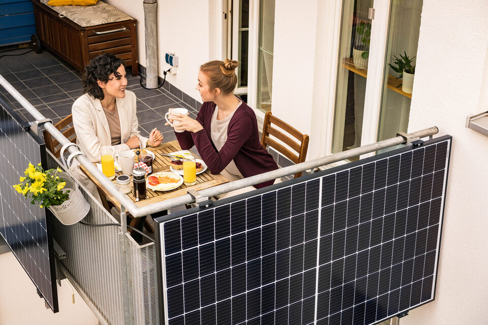 Zwei Frauen frühstücken auf einem Balkon mit Balkonkraftwerk