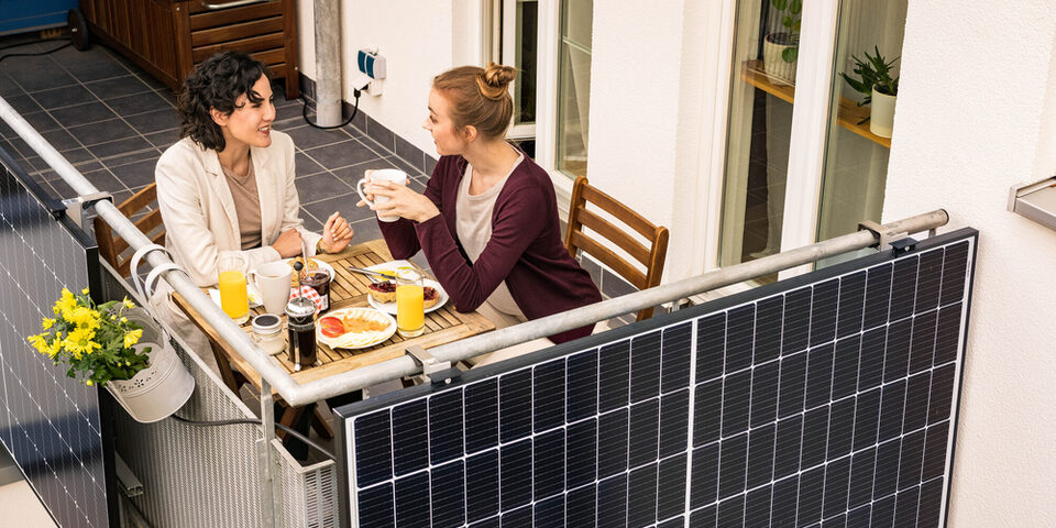 Zwei Frauen frühstücken auf einem Balkon mit Balkonkraftwerk