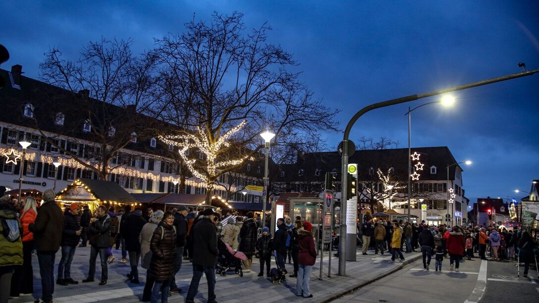 Weihnachtsmarkt auf dem Marktplatz 2023: Blick auf die Frankfurter Straße, auf der sich Menschen tummeln. Im Hintergrund Lichter und geschmückte Buden.