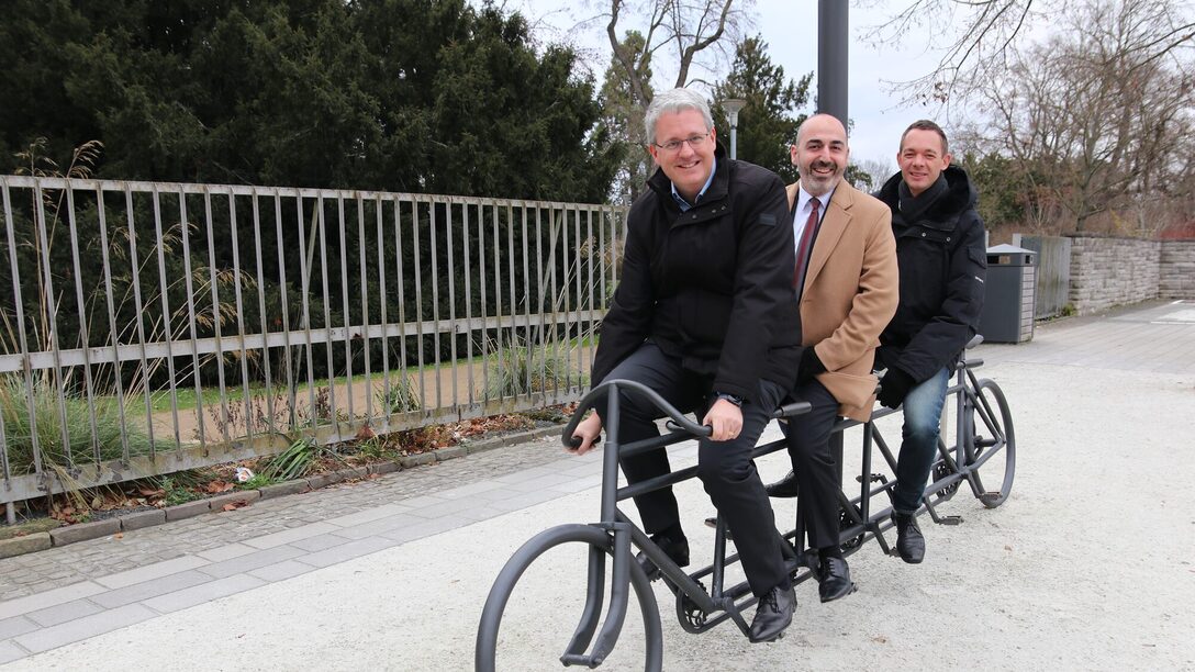 Das neue Dezernenten-Trio sitzt auf einer Nachbildung eines Quintuplets.