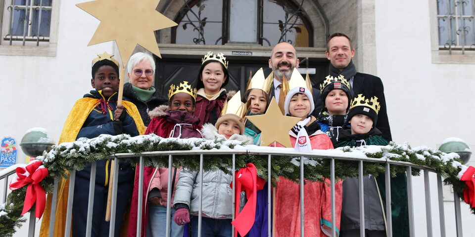 Bürgermeister Murat Karakaya und Stadtrat Simon Valerius gemeinsam mit den Sternensingern vor dem Rathaus in Rüsselsheim am Main