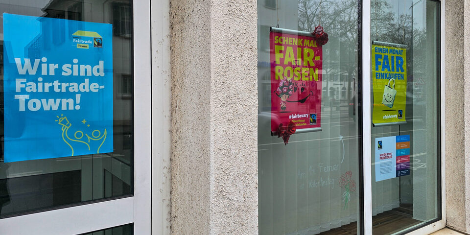 Das Schaufenster des Umweltamts mit Plakaten zum Aktionsmonat Fairbruary. Auf einem Plakat steht "Wir sind Fairtrade-Town", auf einem anderen "Schenk mal Fair-Rosen".