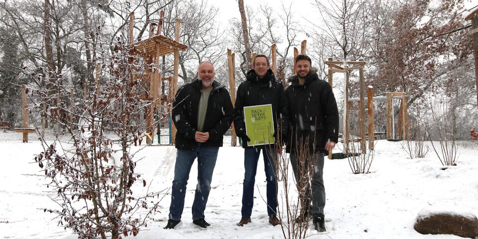 Vertreter der Stadt und des Städteservices im Schnee vor Strauchpflanzungen, bei denen Pflanzenkohle verwendet wurde.