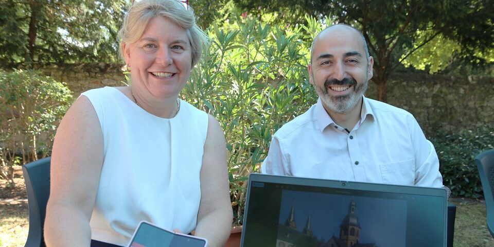 Tanja Koerwer zeigt neben Bürgermeister Karakaya Fotos vom Urlaub ohne Koffer