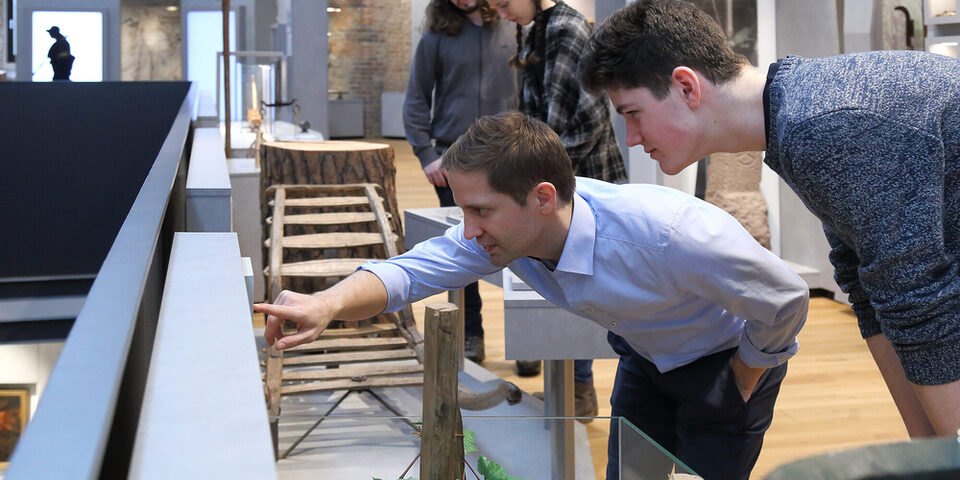 Museumsbesucher lesen aufmerksam eine Informationstafel