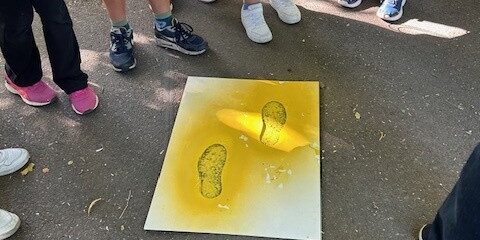 Eine Schülergruppe umkreist die Asphaltmarkierung Gelbe-Füße