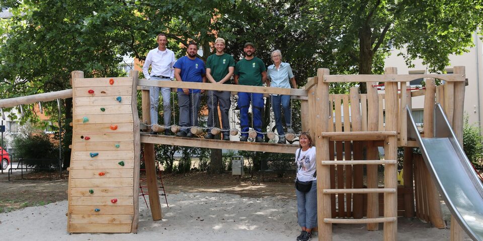 Spielplatz Liebigstraße, Auf dem Steg seht Stadtrat Simon Valerius mit Mitarbeitenden der Spielplatzcrew des Städteservices. Unten steht Frau Beate Bopp von der städtischen Grünplanung.