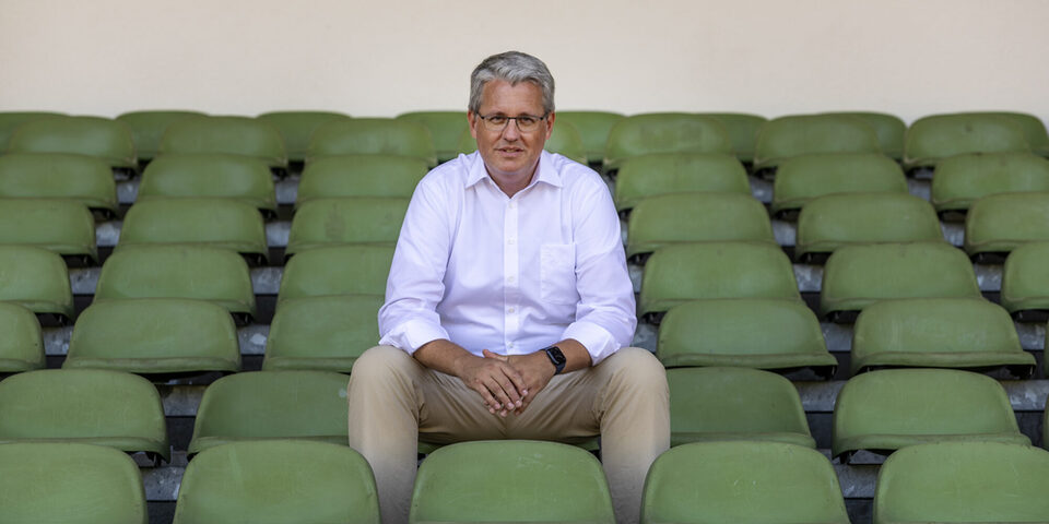 Oberbürgermeister Patrick Burghardt sitzt auf der Stadiontribüne.