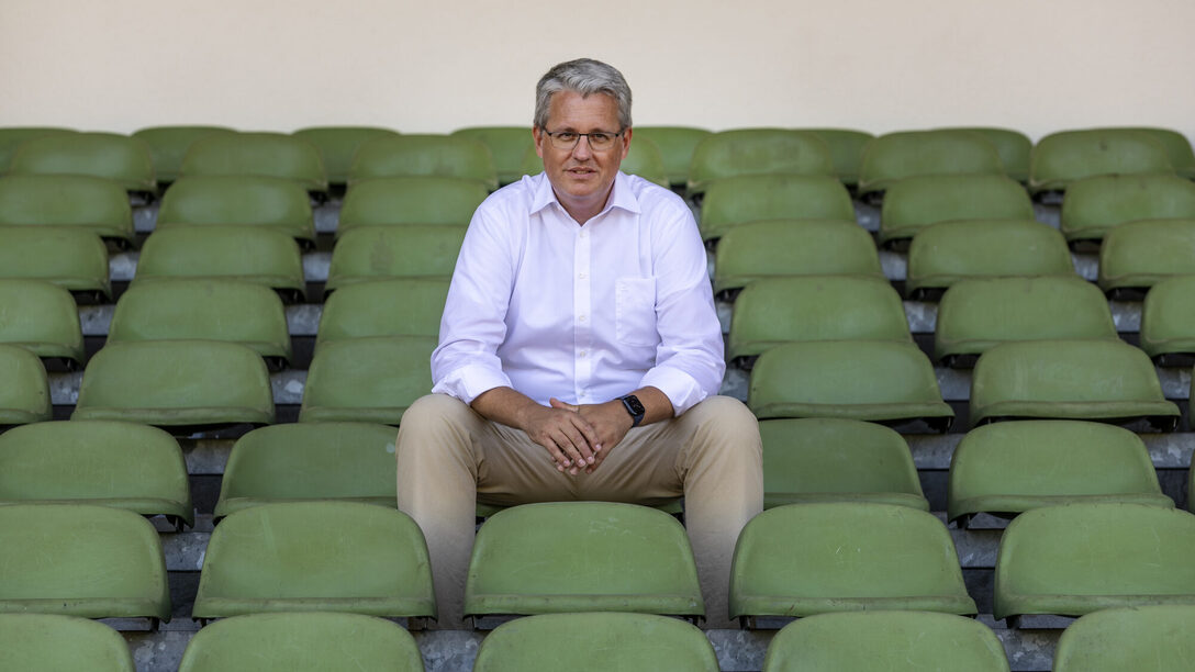 Oberbürgermeister Patrick Burghardt sitzt auf der Stadiontribüne.