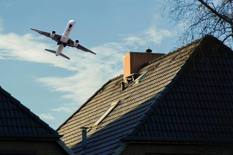 Flugzeug fliegt über ein Wohnhaus