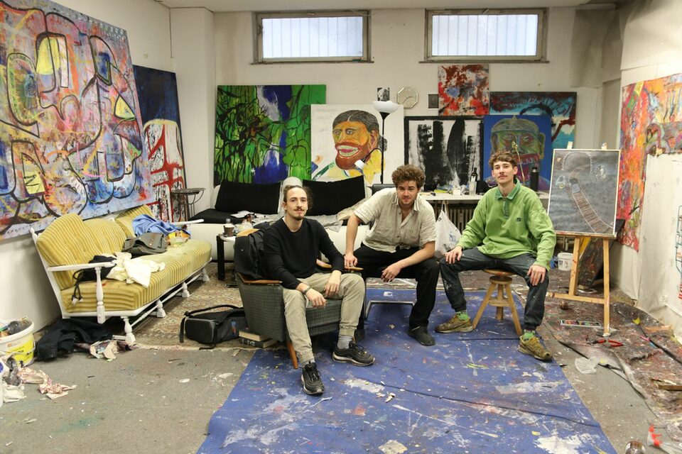 Die drei Künsterler von club d'art percevant sitzen inmitten von Werken im freiraum f3