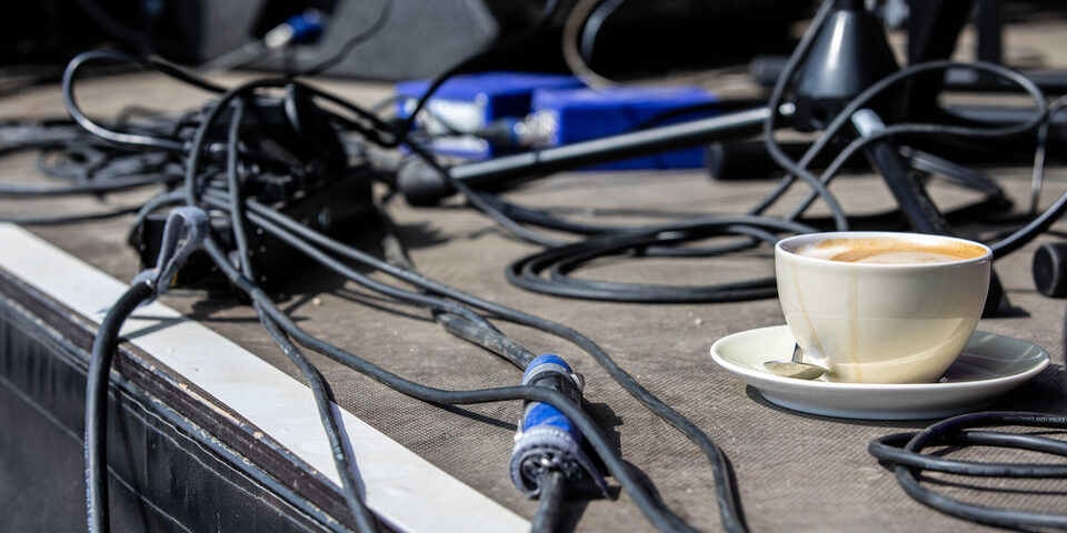 Elektroverkabelung für eine Veranstaltung, inmitten der Kabel steht eine Kaffeetasse