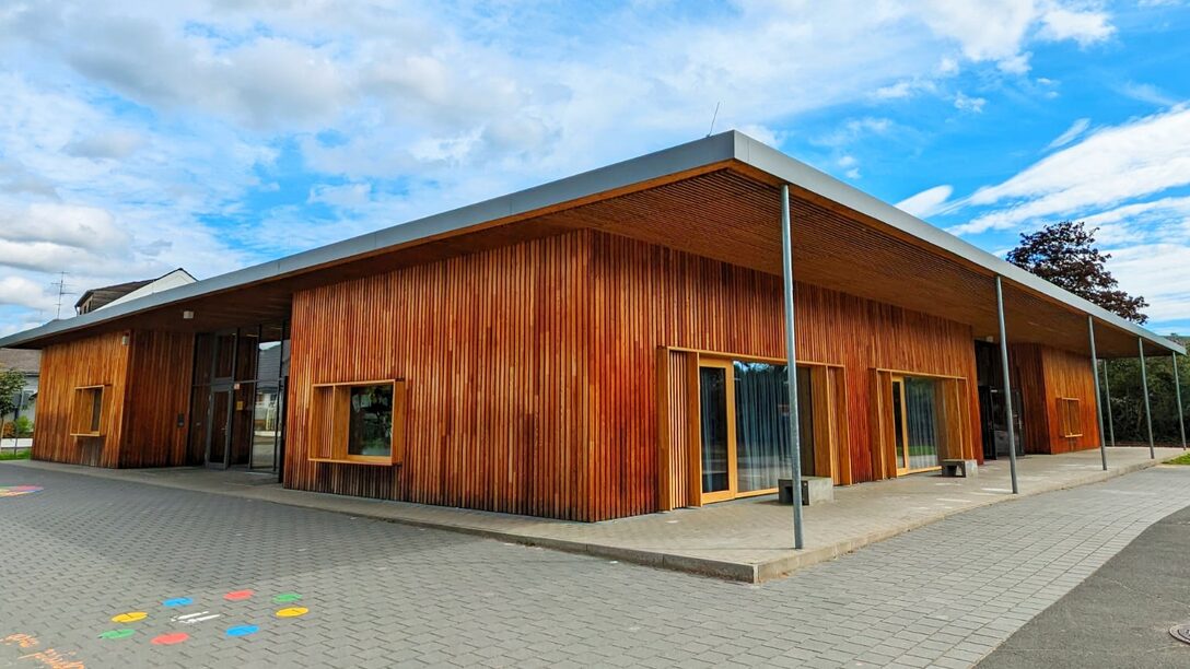 Eingeschossiger Schulbau mit Flachdach und Holzverkleidung, das von großen Fenstern gerahmt wird