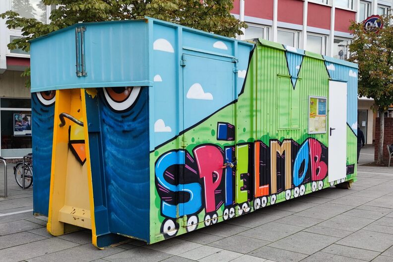 Container auf dem Bahnhofsplatz mit Graffiti-Schriftzug "Spielmobil"