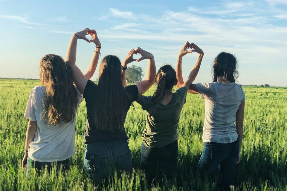 Frauen formen, in einem Getreidefeld stehend, ein Herz mit ihren Händen