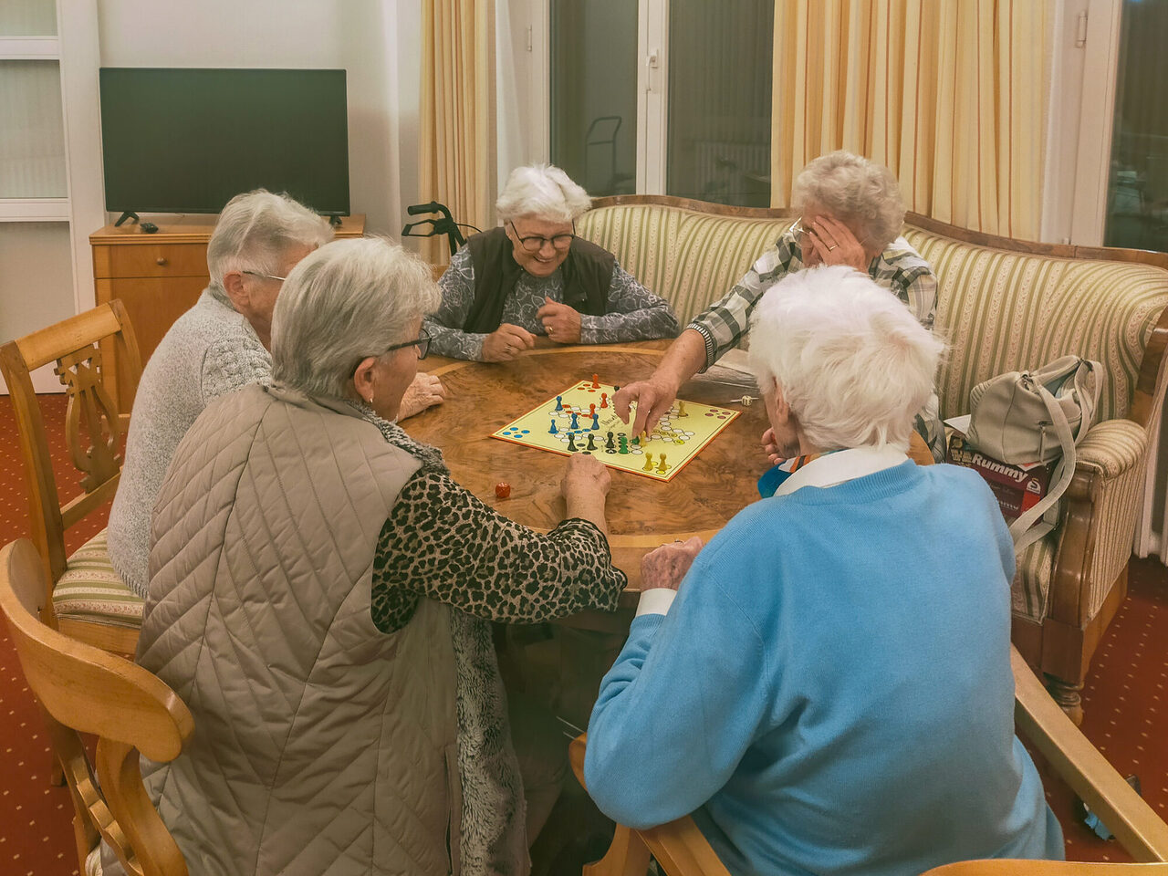 Ältere Damen sitzen am Tisch und spielen das Brettspiel "Mensch ärgere dich nicht."