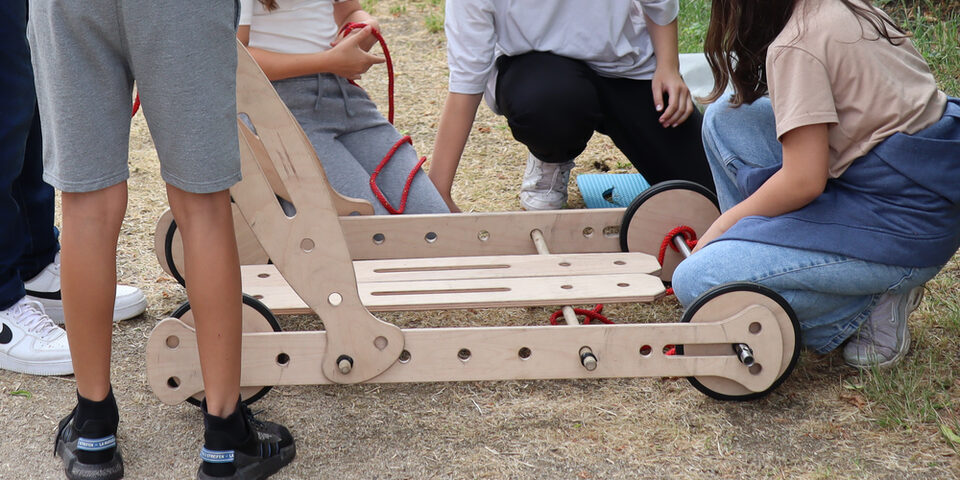 Jugendliche stehen und hocken um eine selbstgebaute Seifenkiste herum