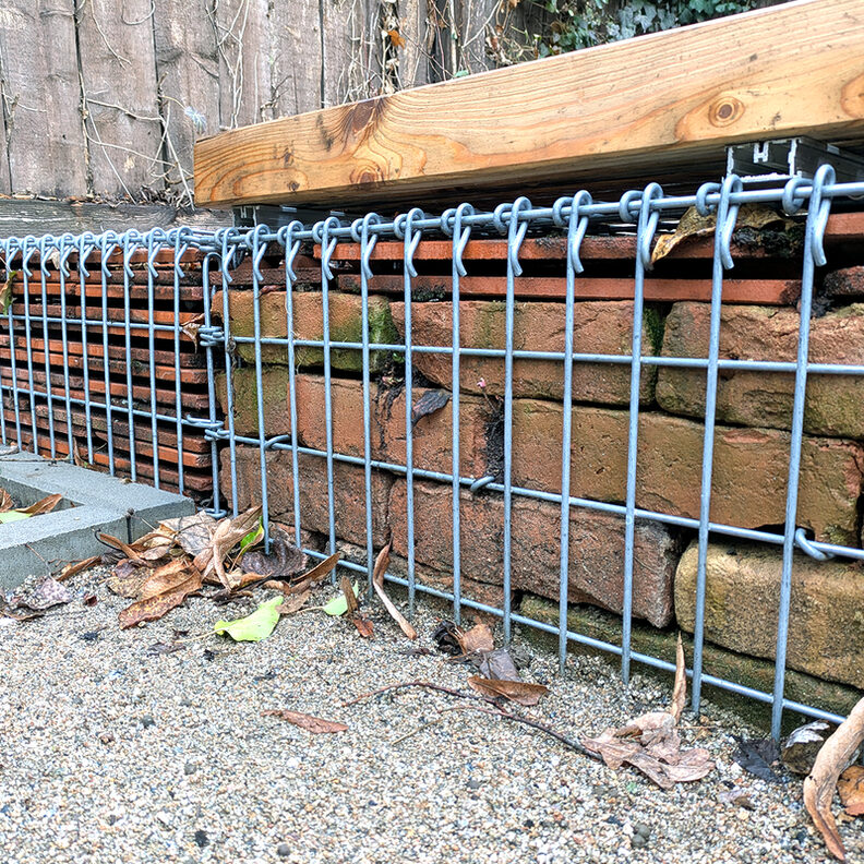 Gabionenfüllung mit Ziegelsteinen (ehemalige Mauer) und Dachziegeln der ehemaligen Dachflächen