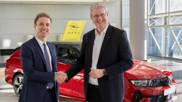 Rüsselsheims Oberbürgermeister Patrick Burghardt (rechts) und Opel CEO Florian Huettl (links) stehen vor einem Opel-Oldtimer und schütteln sich die Hand.