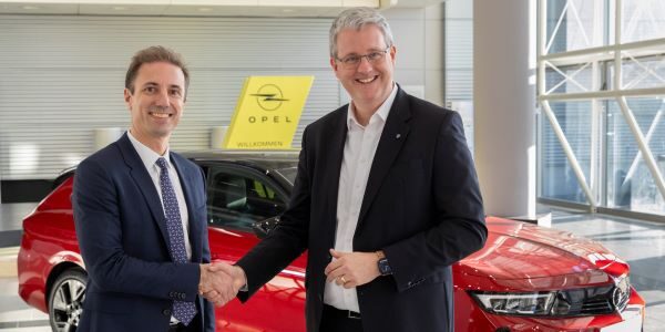 Rüsselsheims Oberbürgermeister Patrick Burghardt (rechts) und Opel CEO Florian Huettl (links) stehen vor einem Opel-Oldtimer und schütteln sich die Hand.