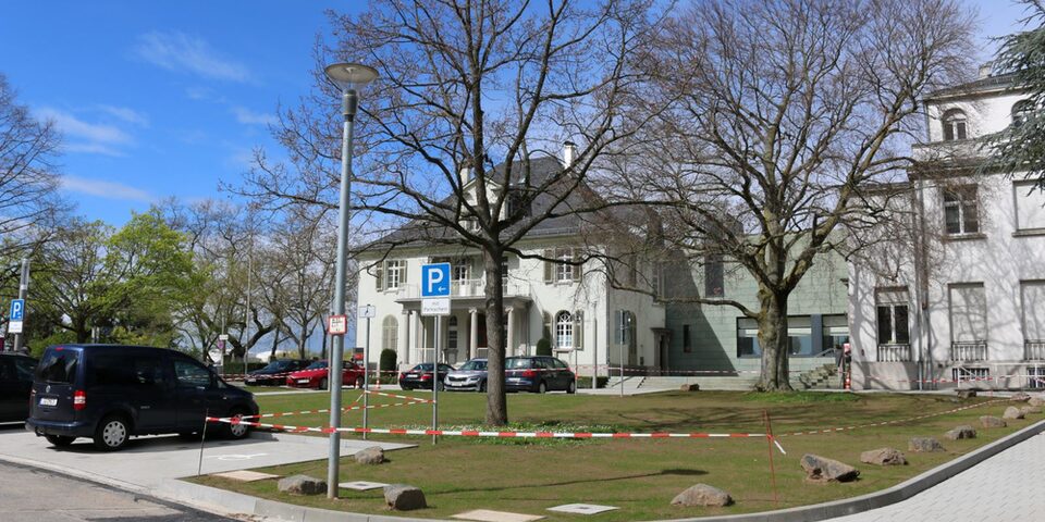 Sanierung der Freiflächen vor den Opelvillen, die Baustelle ist mit Flatterband abgetrennt. Im Hintergrund das Gebäude der Opelvillen.