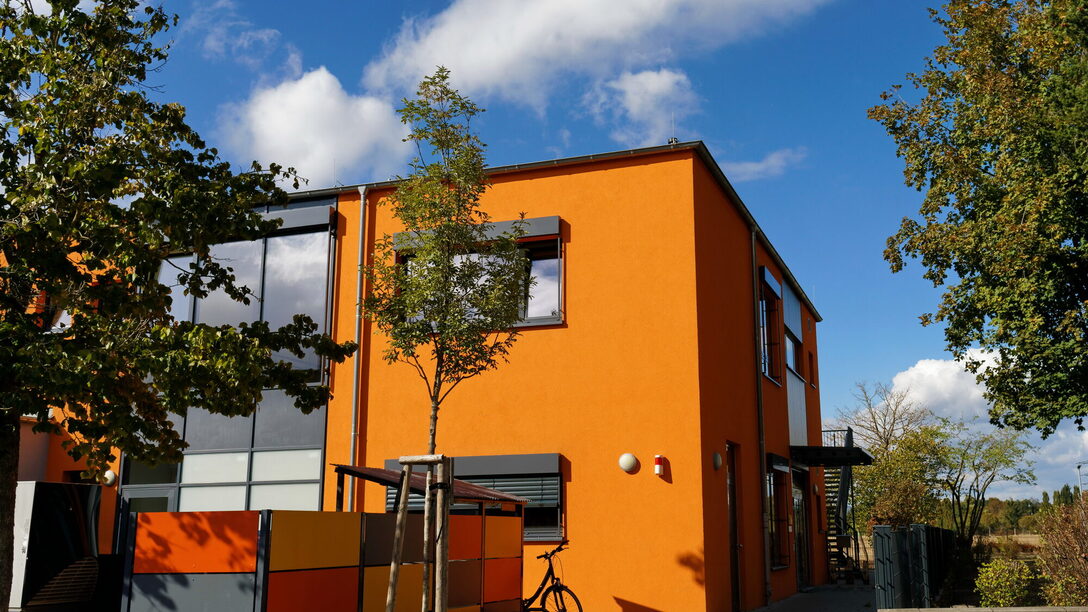 Außenansicht der zweigeschossigen, orange-gestrichenen Kita Karlsbader Straße